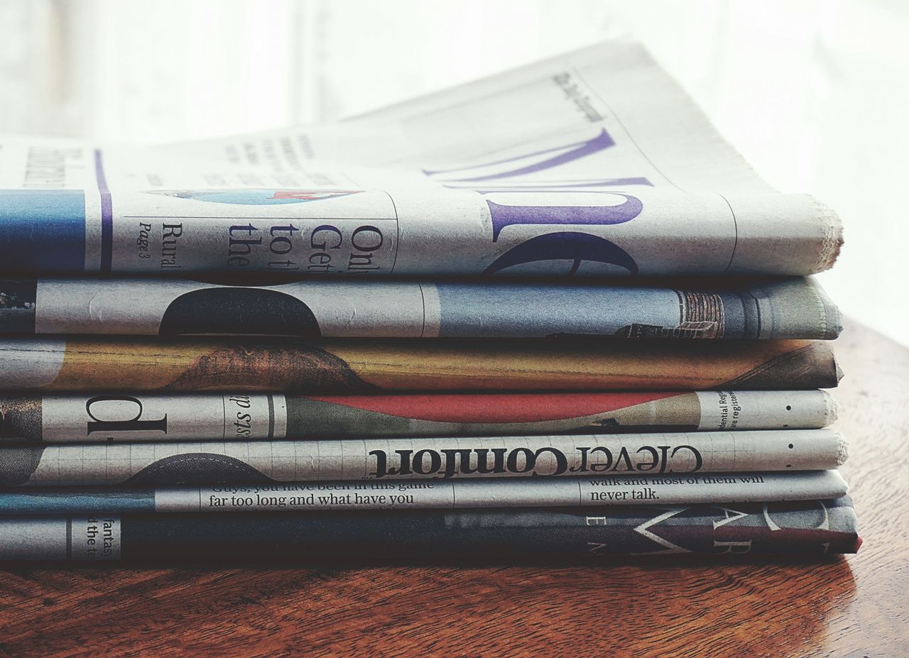 Crafting Captivating Headlines: Your awesome post title goes here A stack of folded newspapers placed on a wooden table, symbolizing news and information.